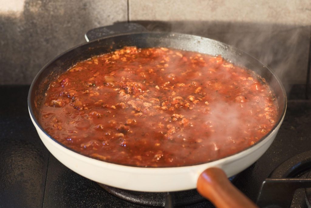 Homemade Meat Sauce Recipe simmering in a pan with ground beef and tomatoes